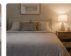 Neatly made bed at a comfortable height with bedside table